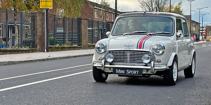 Classic Mini EV driving outside of Burnley F.C Stadium.